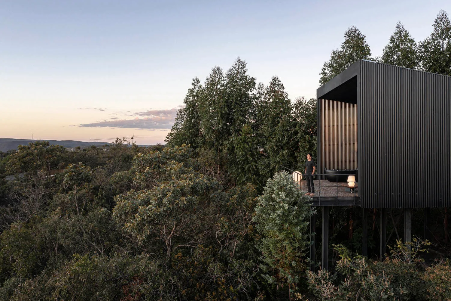 A modern, metal-clad building nestled in a forest.