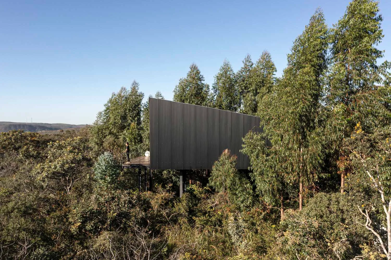 A modern metallic building exterior surrounded by trees