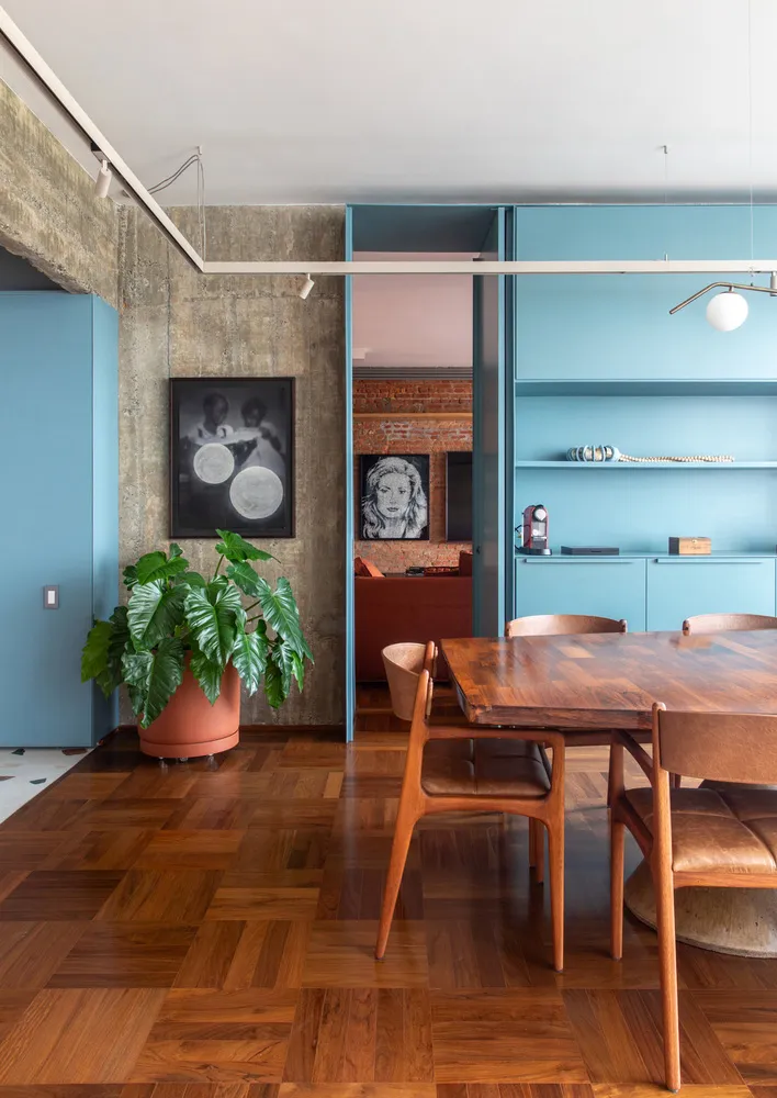 A modern living room with wooden floors, blue cabinets, and a potted plant.