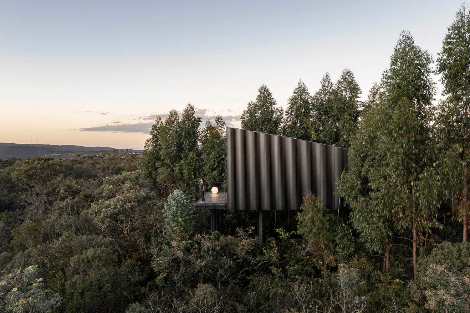 A modern home with a metal-clad exterior, surrounded by trees.
