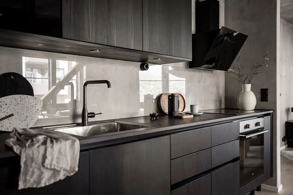 Kitchen with black wooden cabinets and a concrete backsplash.