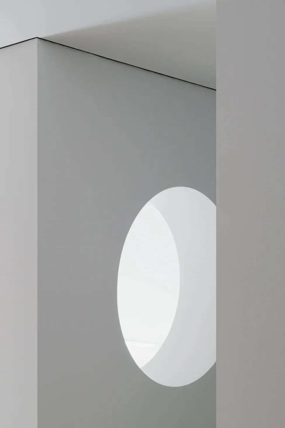 Minimalist interior design featuring a circular cut-out wall in light-grey concrete