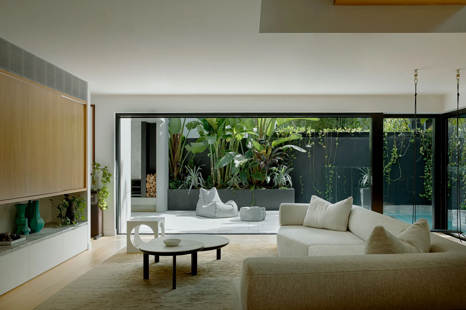 A modern minimalist living room featuring floating furniture, white accents, and a view of a tropical garden with a floating 