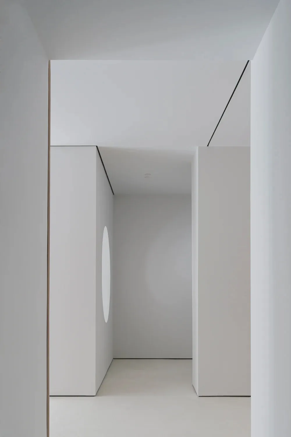 A minimalist modern living room with white concrete walls and a circular cut-out feature.