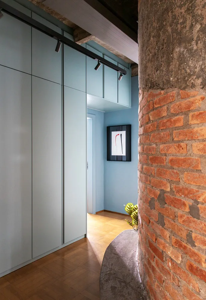 A minimalist interior space with concrete walls, a wooden floor, and a plant.