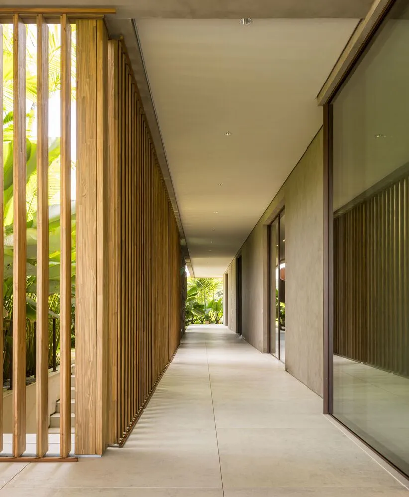A modern corridor featuring wooden walls and floors with a view of greenery outside.