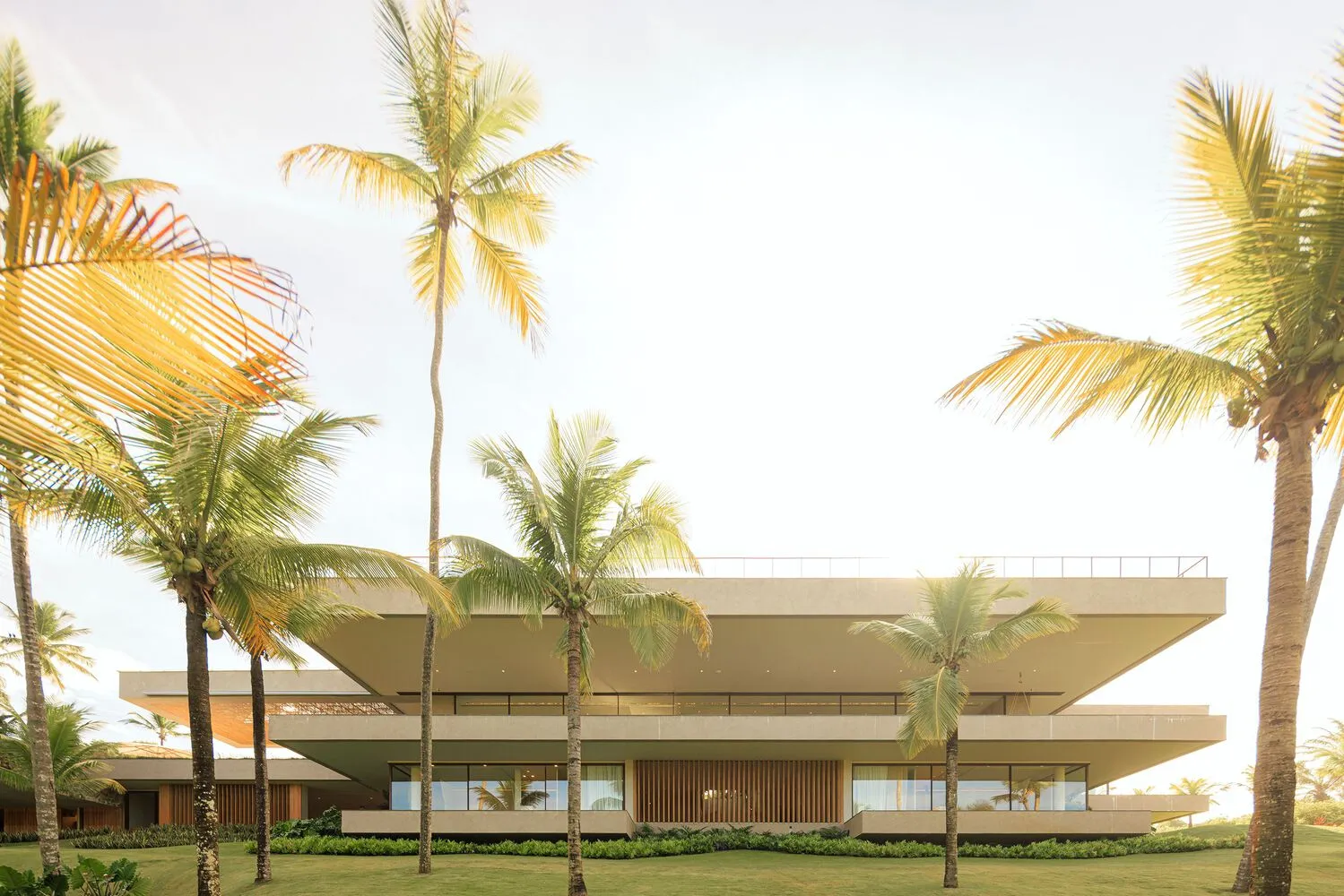 Modern residential building made of concrete, surrounded by palm trees.