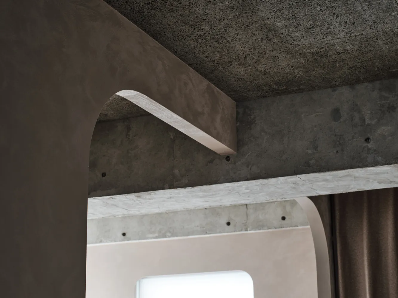 A close-up view of a modern interior featuring a smooth, concrete arch with a textured ceiling and wall.