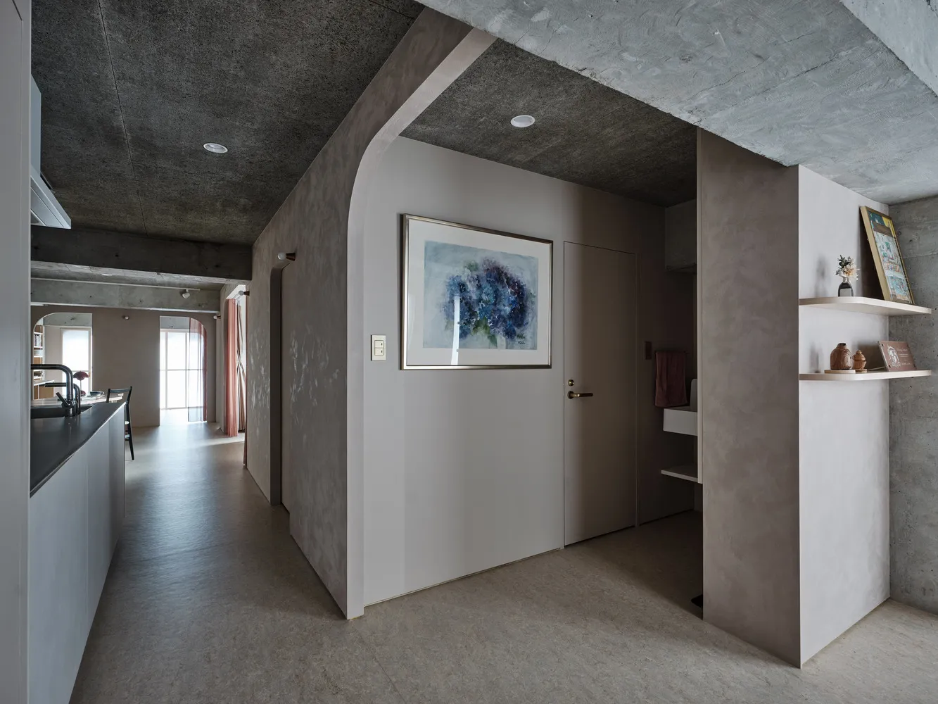 Modern, minimalist residential interior with concrete and plaster walls and a white door with artwork.