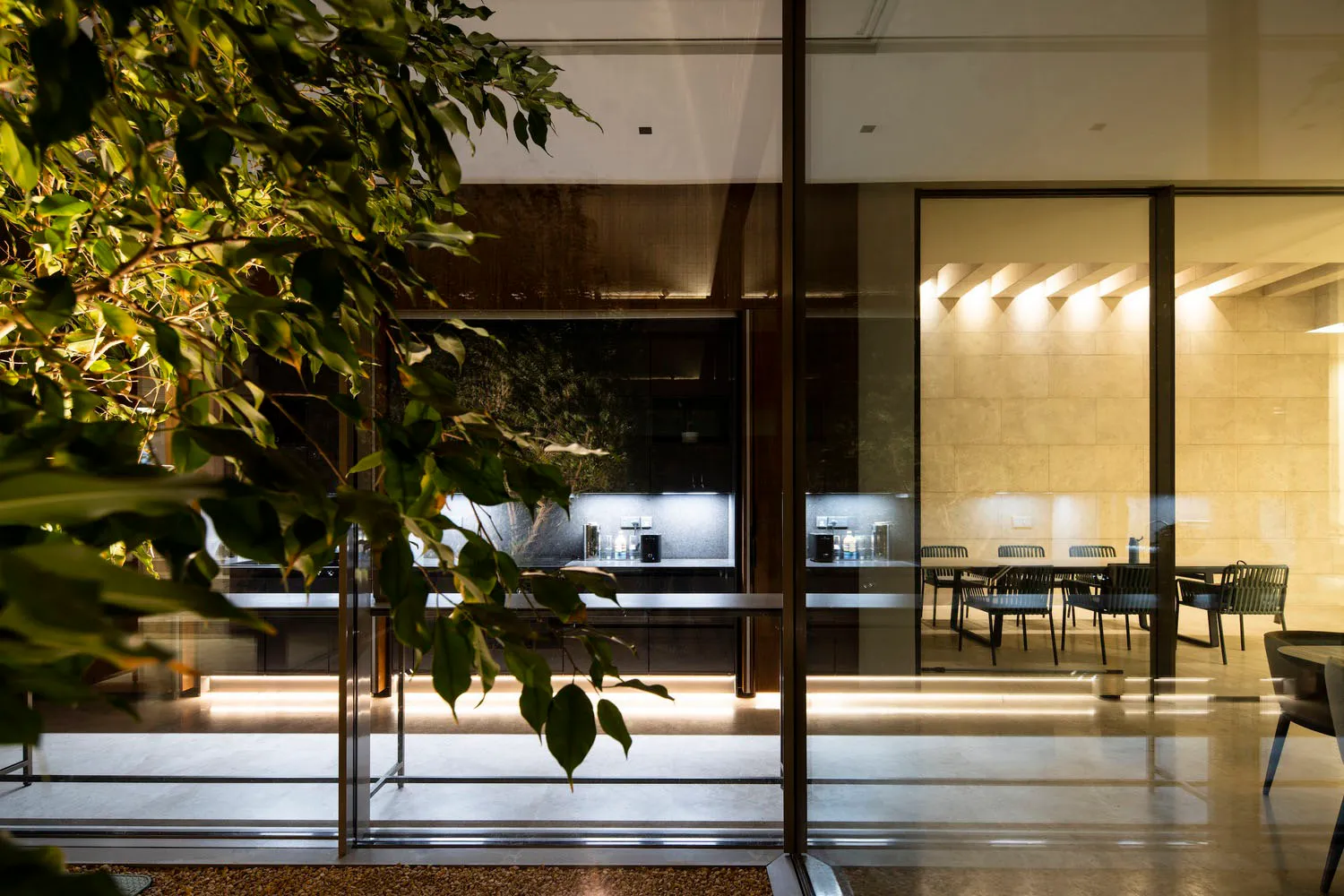 A modern residential dining area featuring concrete, glass, and metal elements.