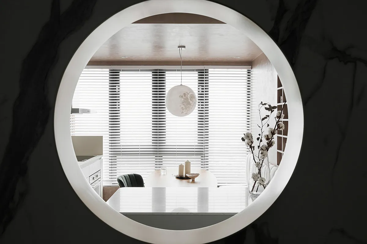 Modern, minimalist residential dining room with white decor and white pendant light hanging from the ceiling.