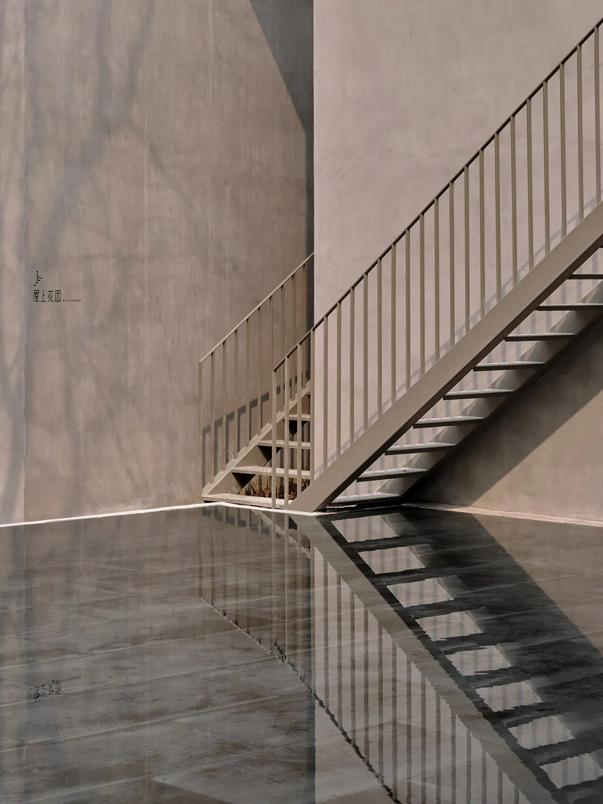 A concrete staircase with a metallic handrail reflected in a glossy floor.