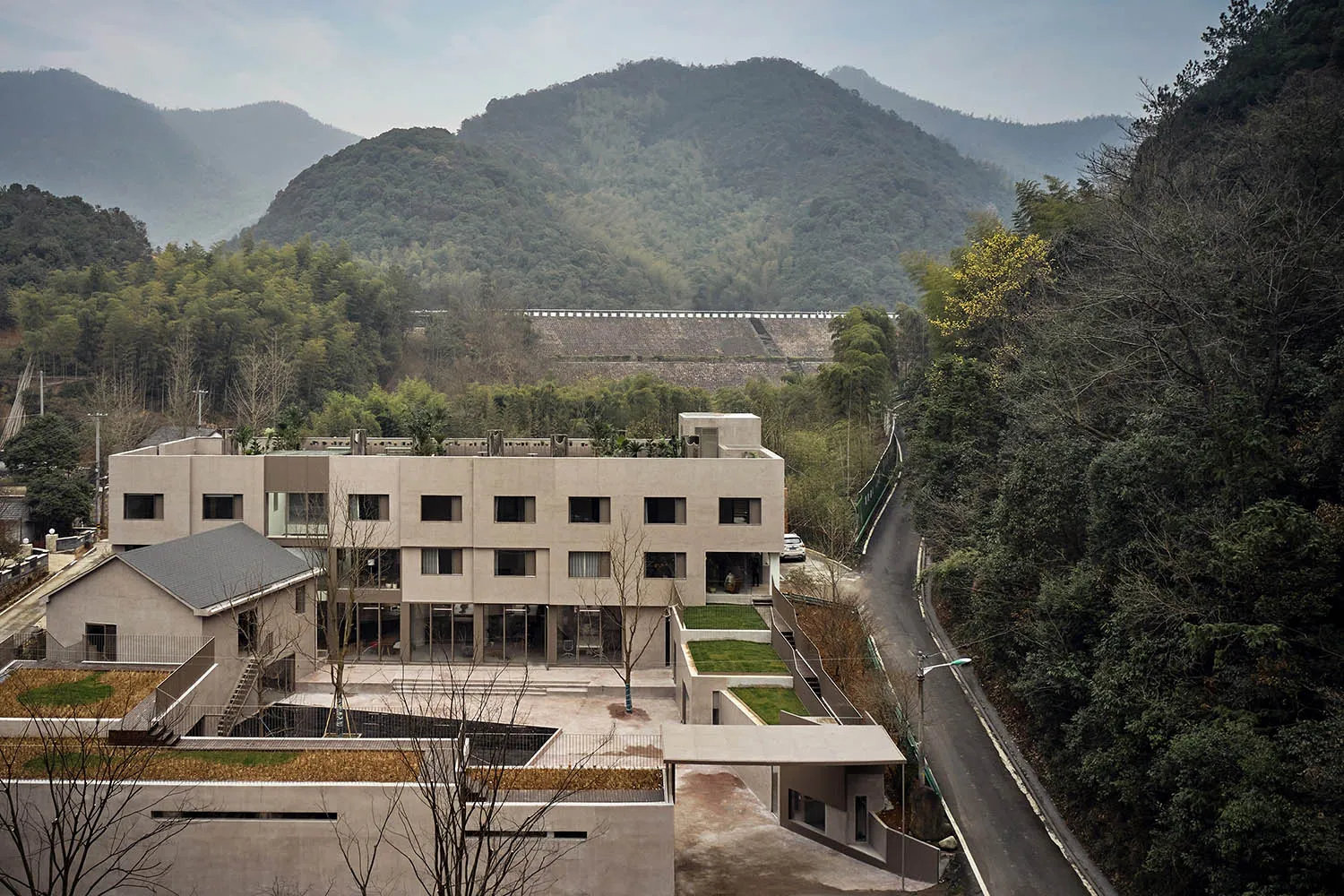 一座現代住宅建築採用混凝土材質,具備簡約設計,並環繞綠意植栽。