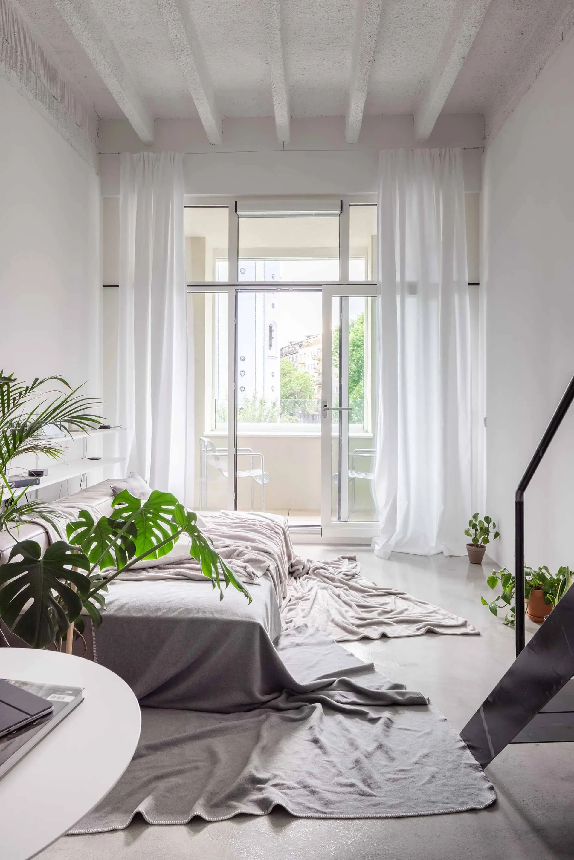 A minimalist bedroom with concrete floor and white walls.
