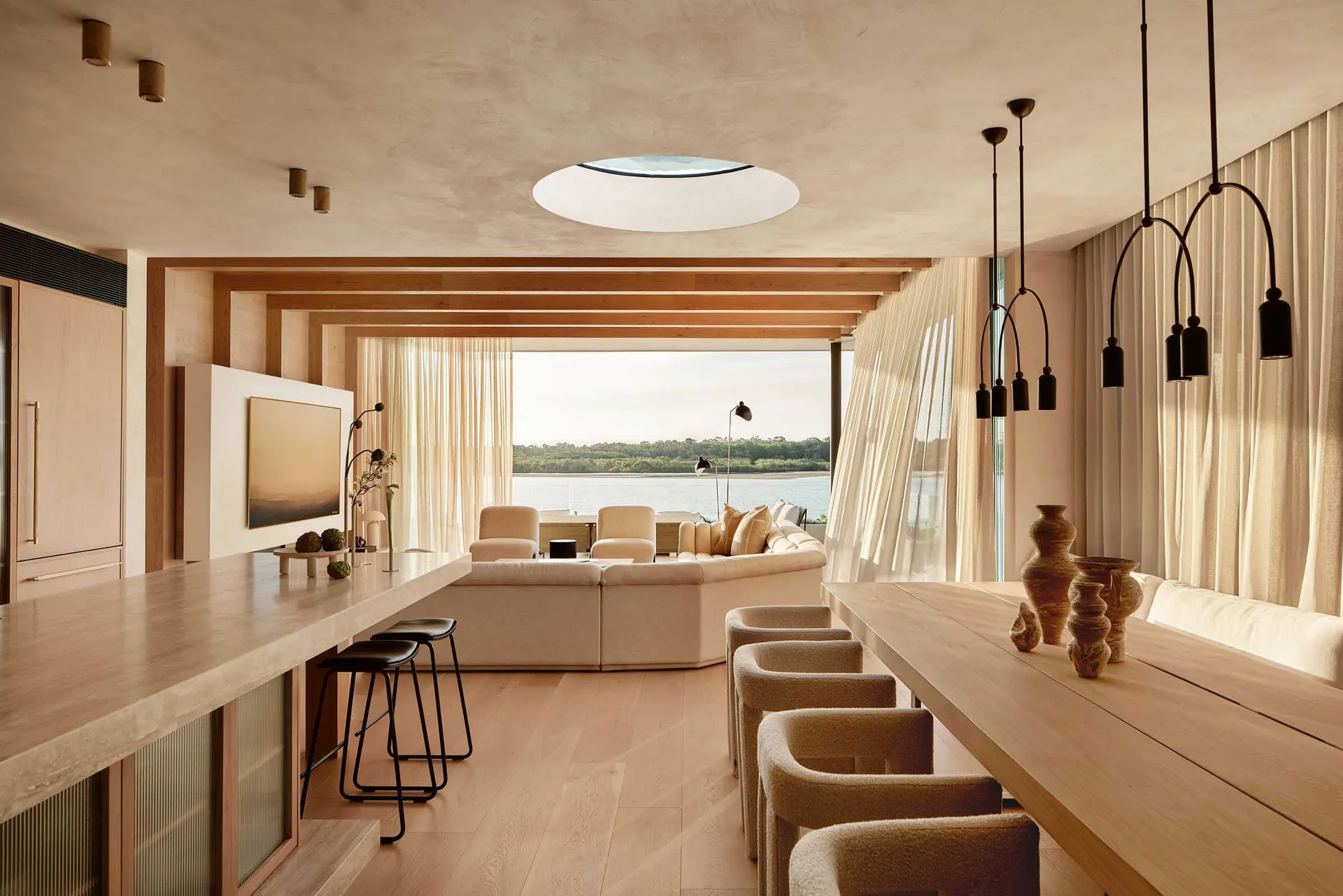 Modern living room with a large sectional sofa, a coffee table, and a mounted television on a wooden wall, with sheer curtain