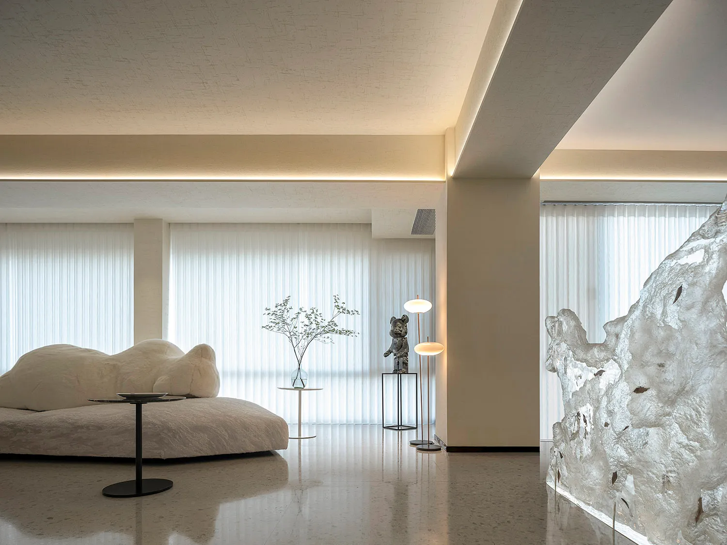 Modern minimalist living room featuring glass and metal elements and white, vertical blinds allowing natural light in.