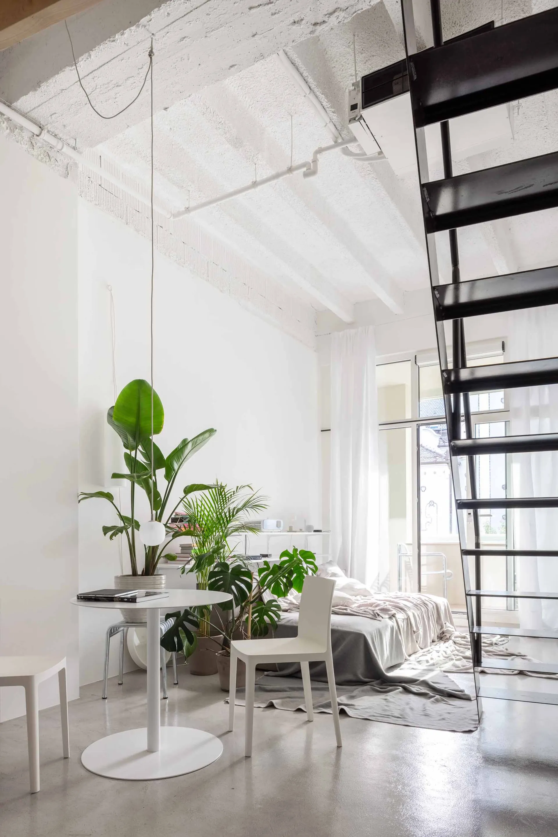 A minimalist living space featuring concrete walls and a large black ladder.