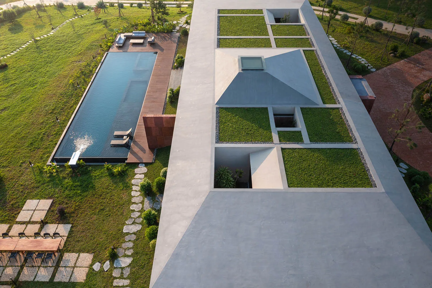 Aerial view of a modern house featuring large concrete structures and glass elements.