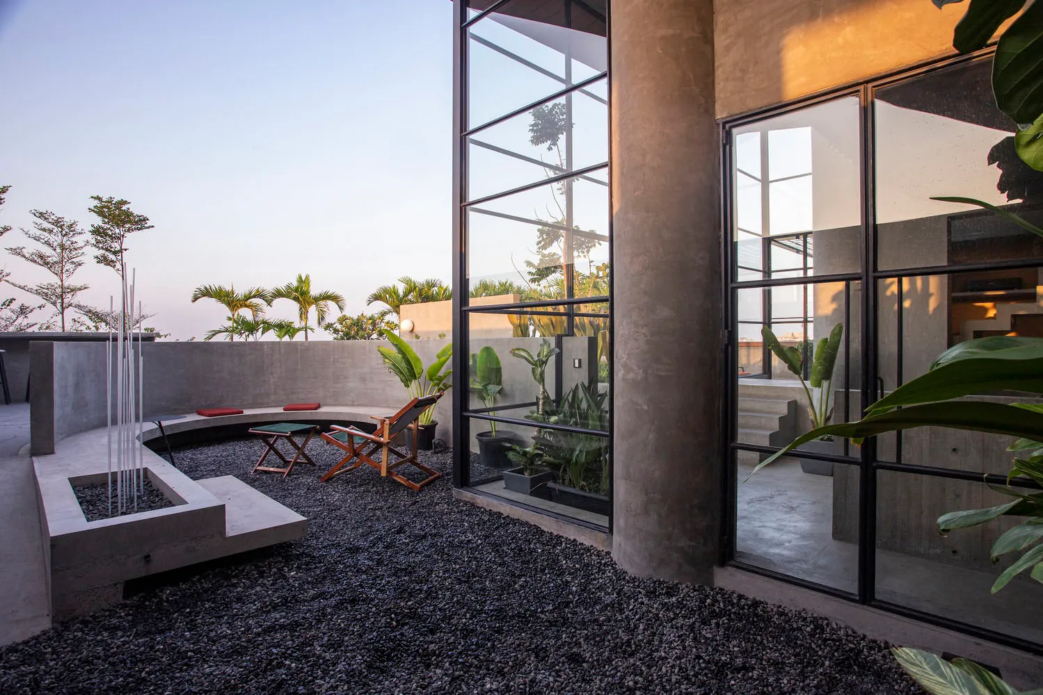 Concrete patio with gravel, modern glass walls, and potted plants