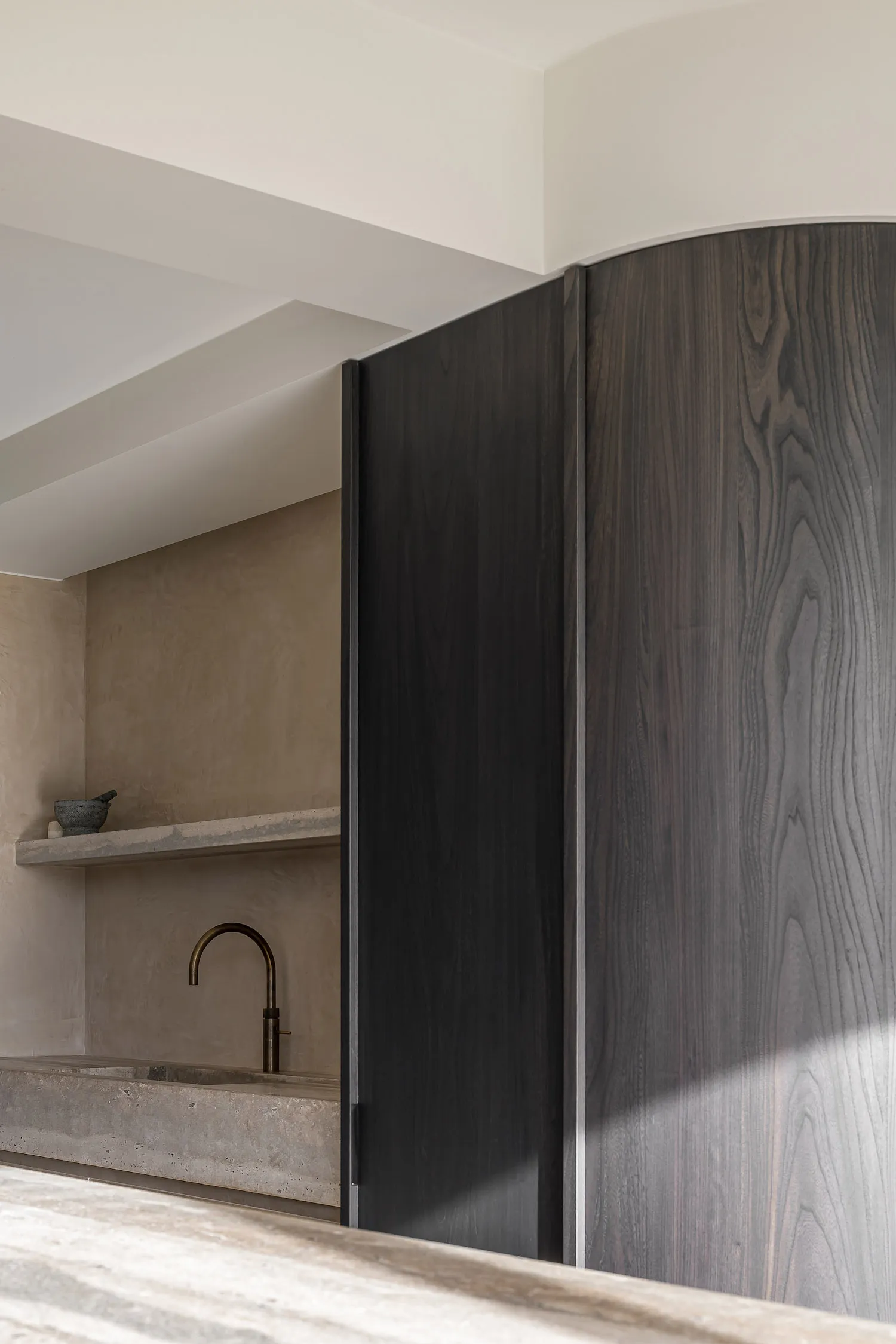 A minimalist interior with dark wooden cabinetry and a concrete countertop.