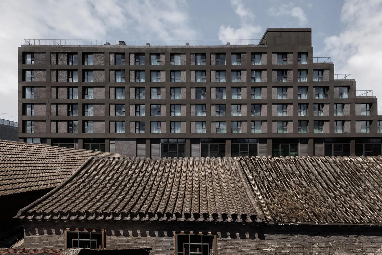 一座現代建築採用混凝土外觀，內部設有大型客廳與大面窗戶。
