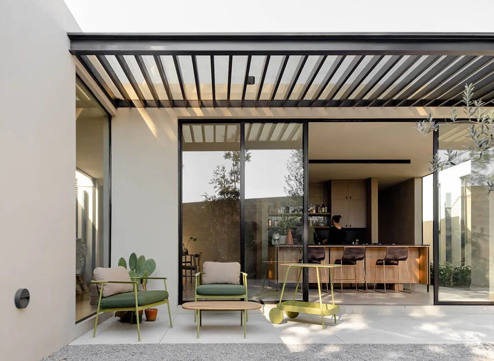 Modern minimalist residential interior featuring exposed steel beams, glass walls, concrete flooring, and wood accents.