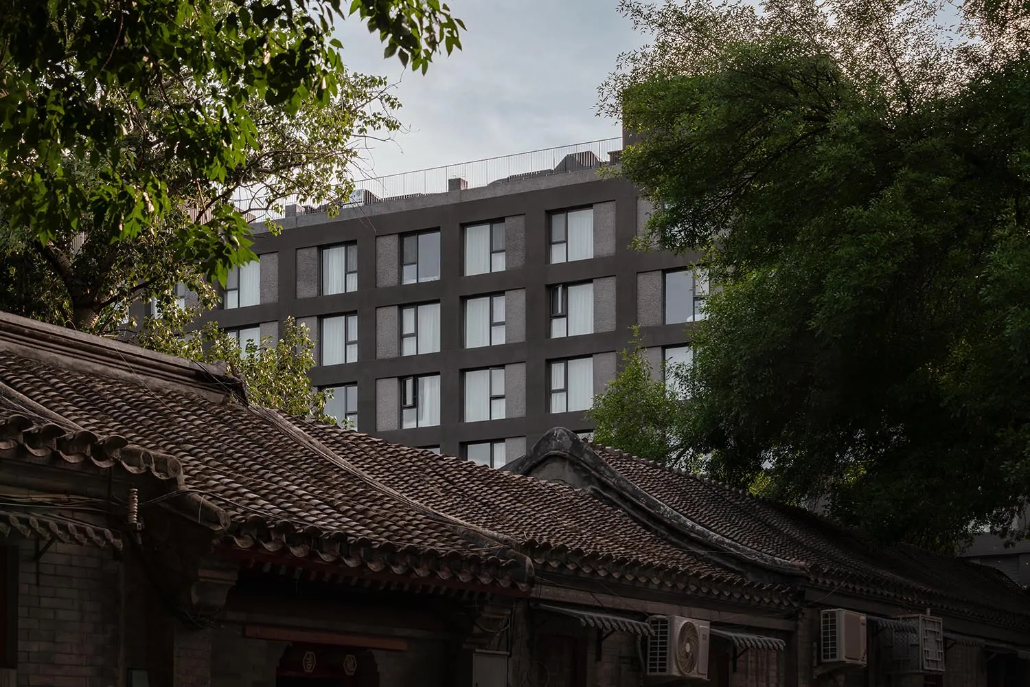 一座現代都市建築,外牆採用混凝土材質並搭配大型窗戶。