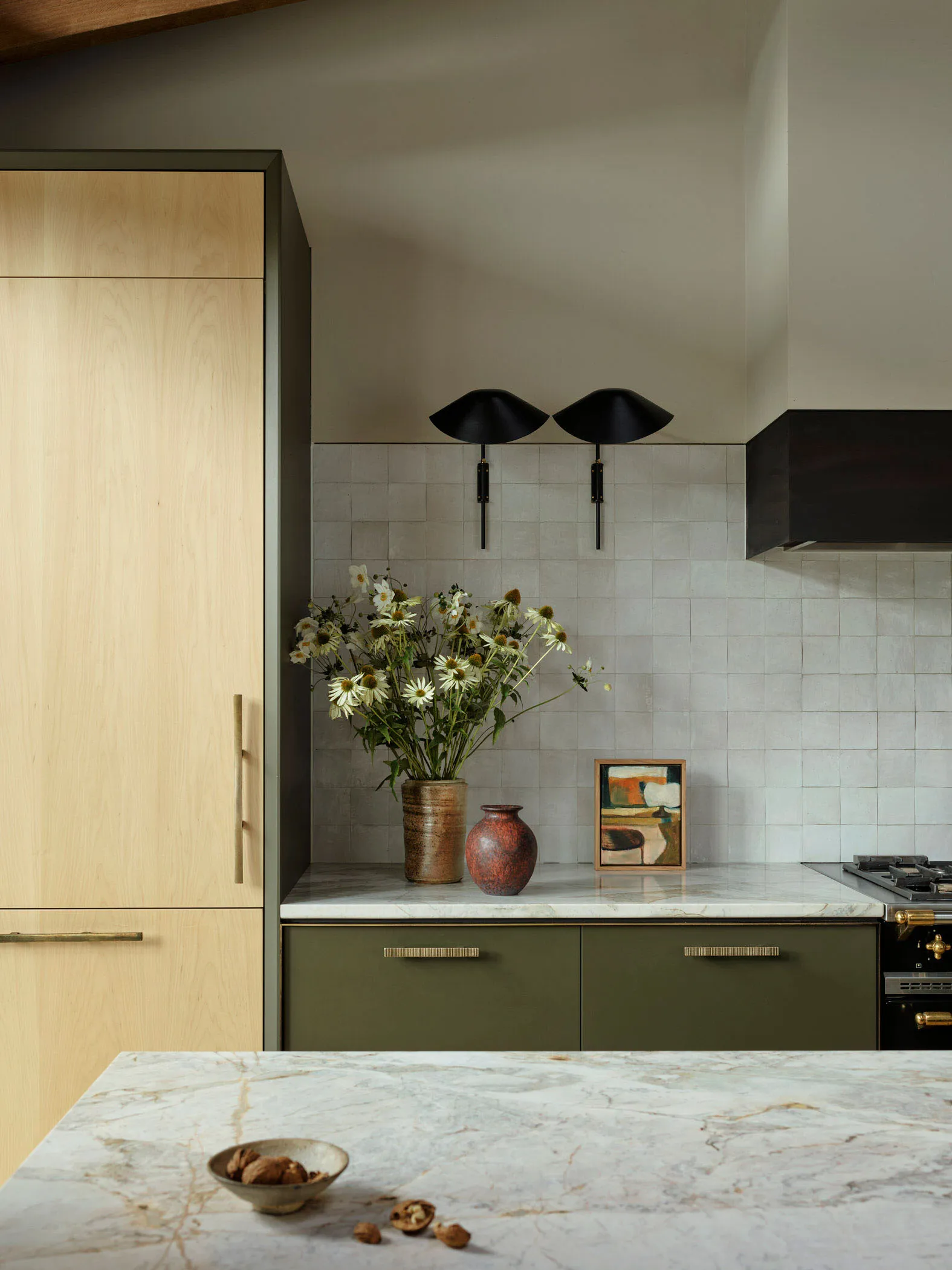 Modern kitchen featuring minimalist design, marble countertops, and green cabinets.