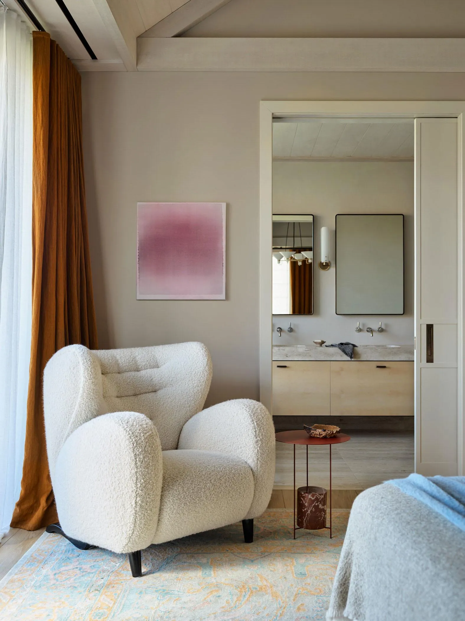 A modern living room featuring a comfortable white wingback chair with a traditional texture, a red side table, and a blue bl