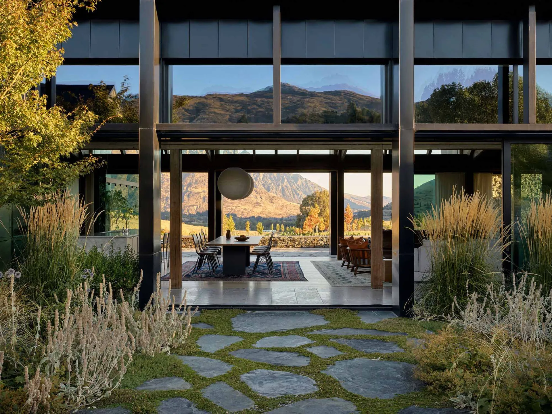 A modern outdoor living area with glass walls and a stone pathway.