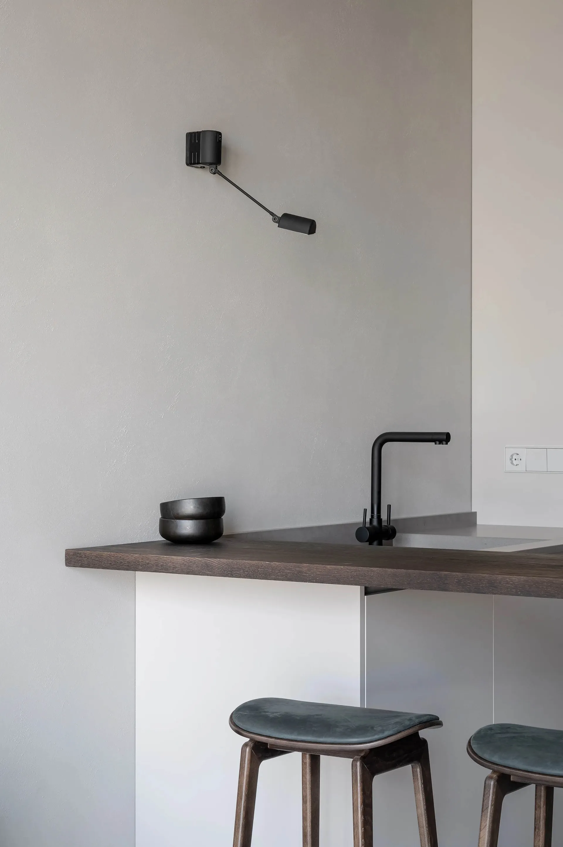 Modern kitchen with a wooden countertop, black faucet, and wall-mounted lamp.