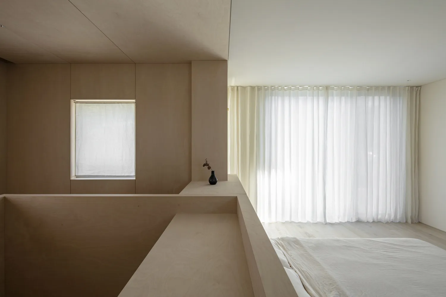 A minimalist bedroom with wooden walls, fabric curtains, and a simple bed setup.
