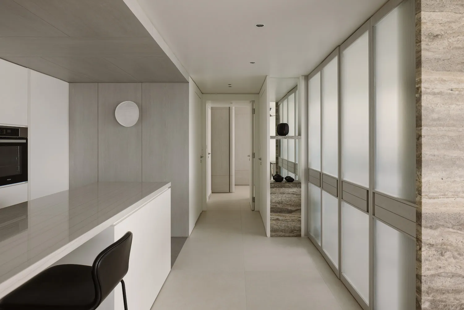 A modern minimalist kitchen featuring white materials, with an open layout and a sleek, minimalistic design.
