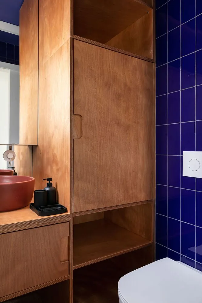 A modern bathroom features wooden cabinets and blue tiles.