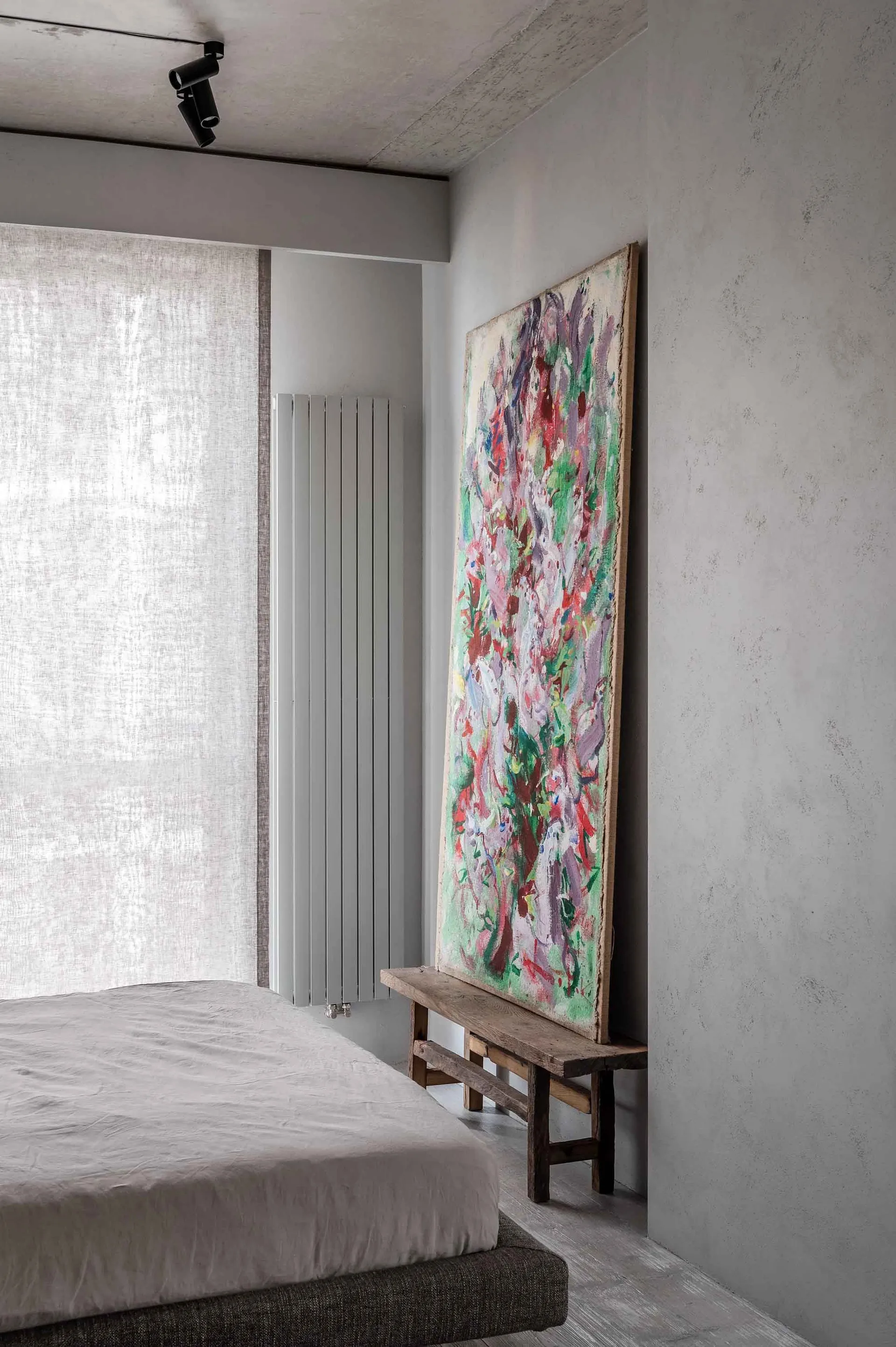 Modern bedroom with a fashionably styled interior, featuring an abstract painting leaning against the wall.