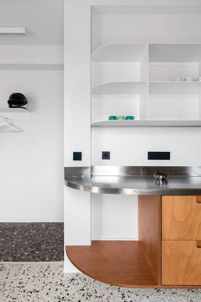 Modern kitchen with metallic countertops, wooden cabinets, and terrazzo flooring.
