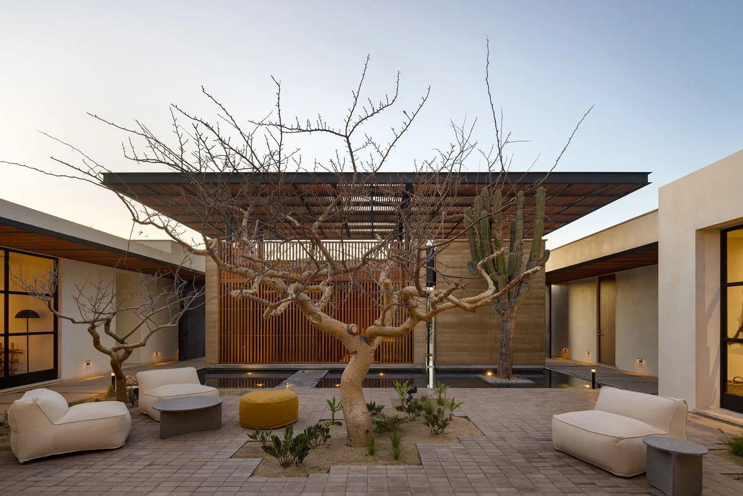 A modern garden lounge featuring concrete furniture, canvas seating, and matte lighting fixtures.