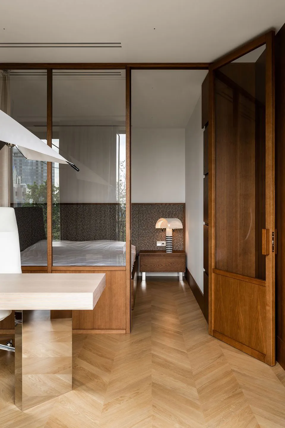 Modern minimalist bedroom with wooden furniture and a white bed.