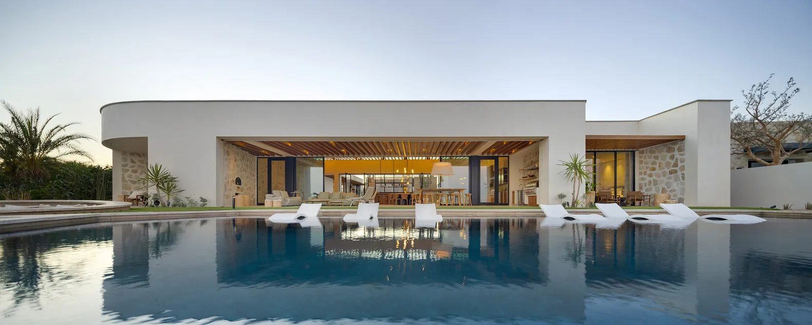A contemporary residential building with a sleek, minimalist design featuring concrete walls and a large open-plan living are