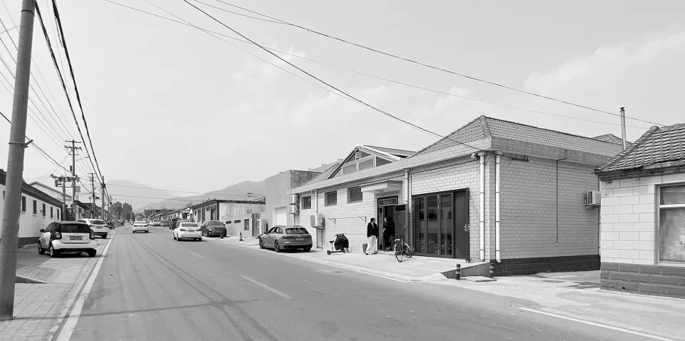 A street view image showing a road with cars, buildings, and electrical wires.