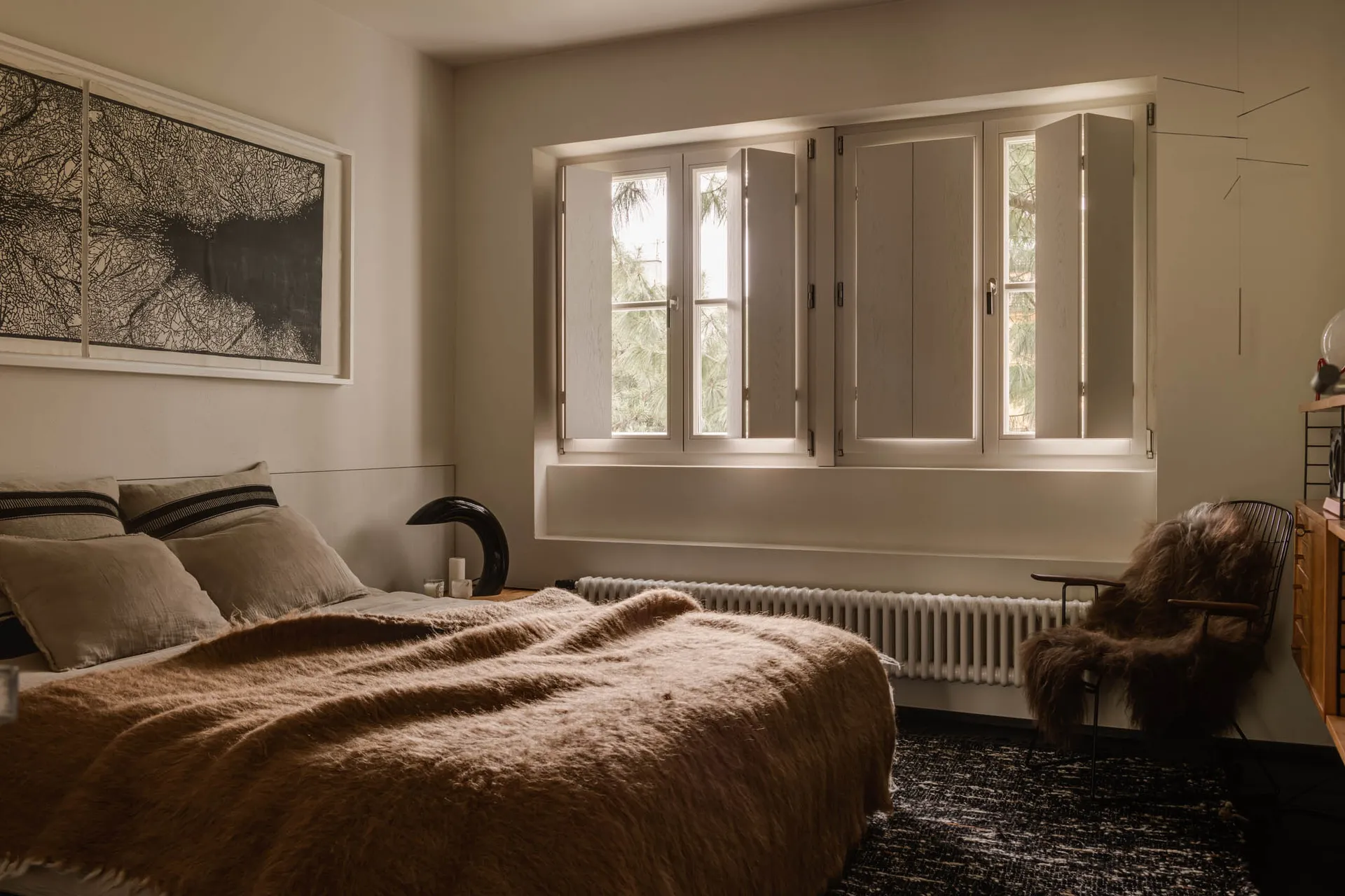 Neutral-toned minimalist bedroom with a bed, window, and chair.