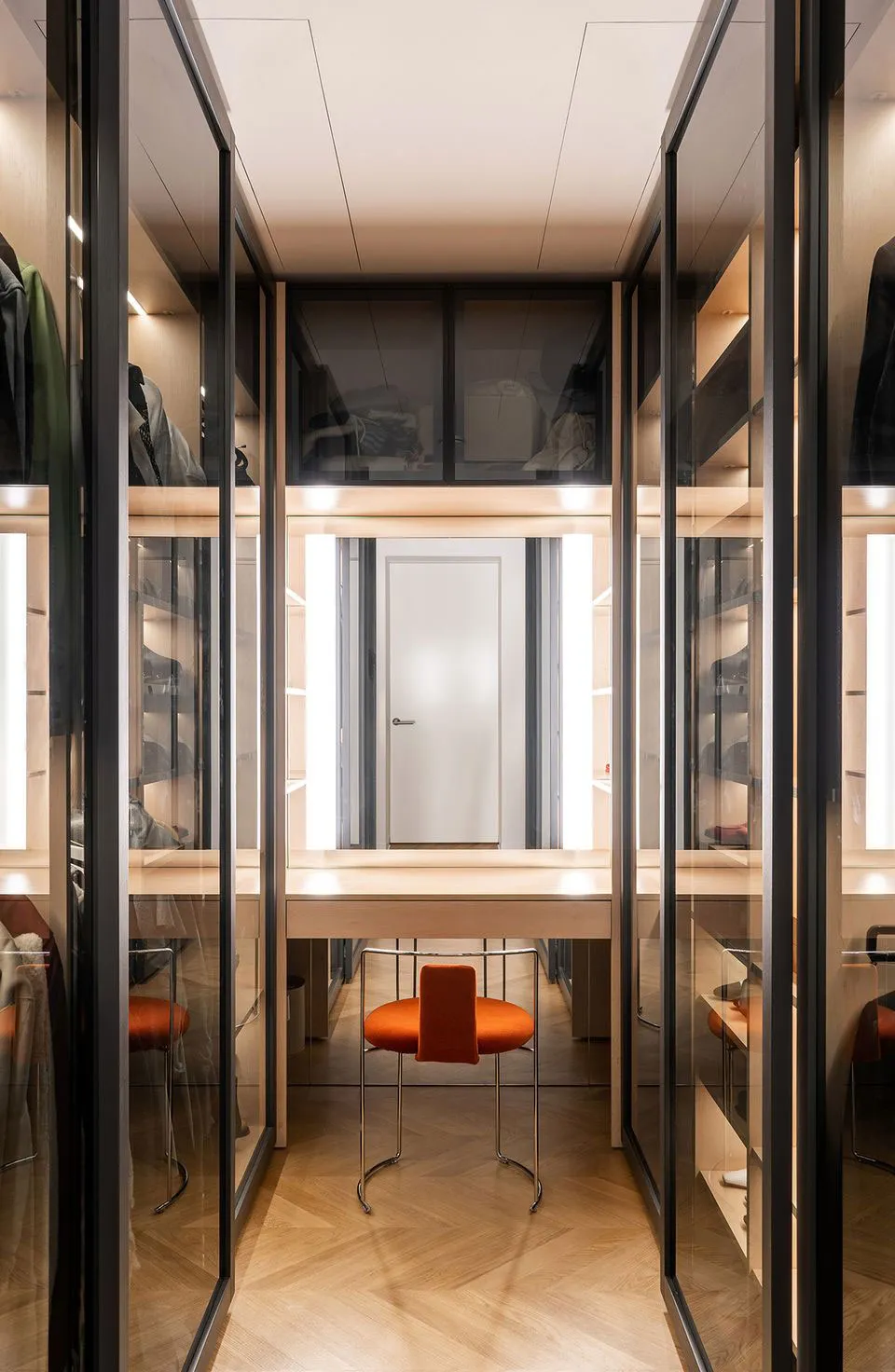 Modern minimalist wardrobe with glass panels and a wooden floor.