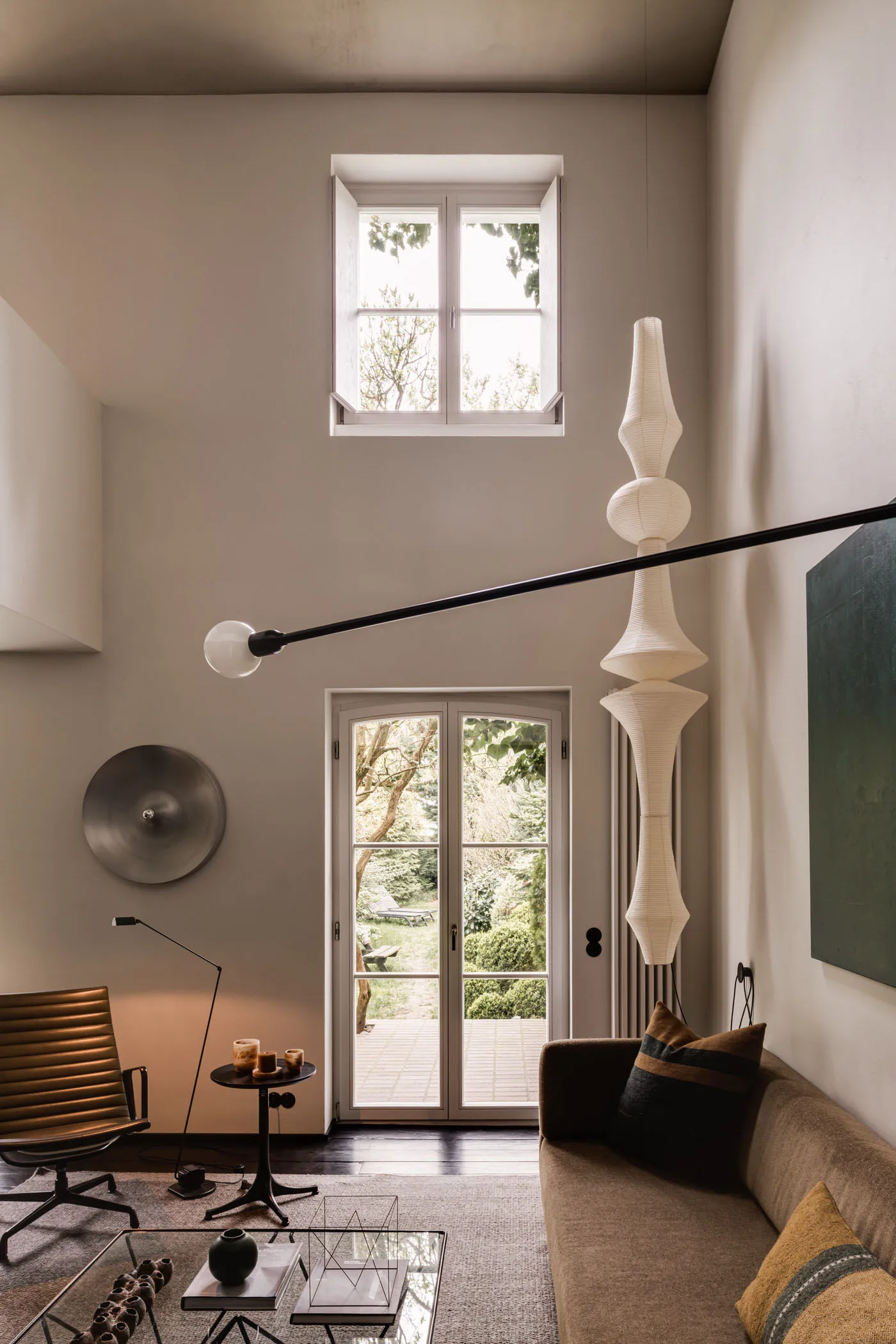 A modern interior design featuring a living room with neutral-toned furniture, a tall floor lamp, and a French door leading t