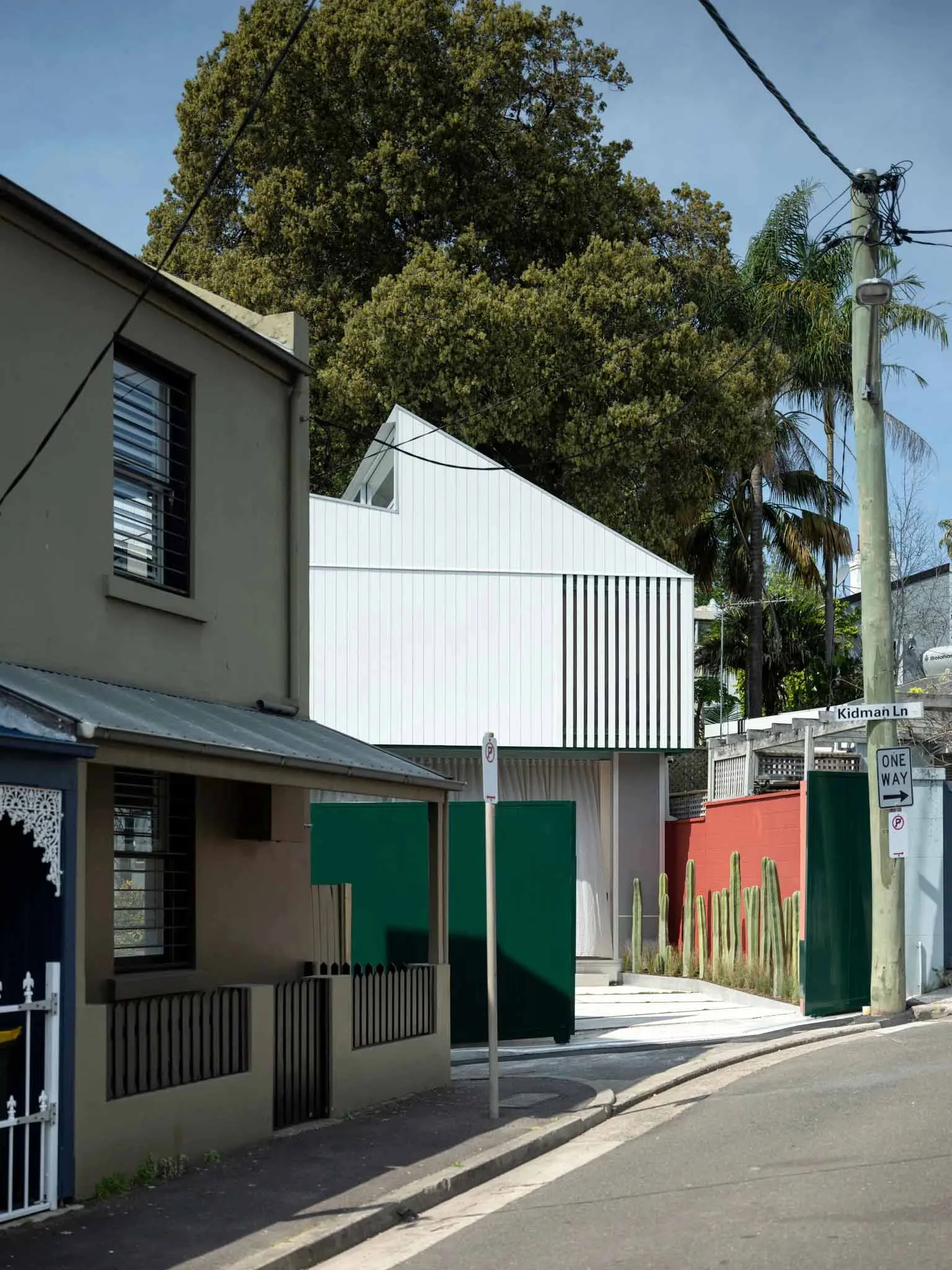 一棟位於住宅街區的現代增建房屋,採用垂直金屬外牆覆層。