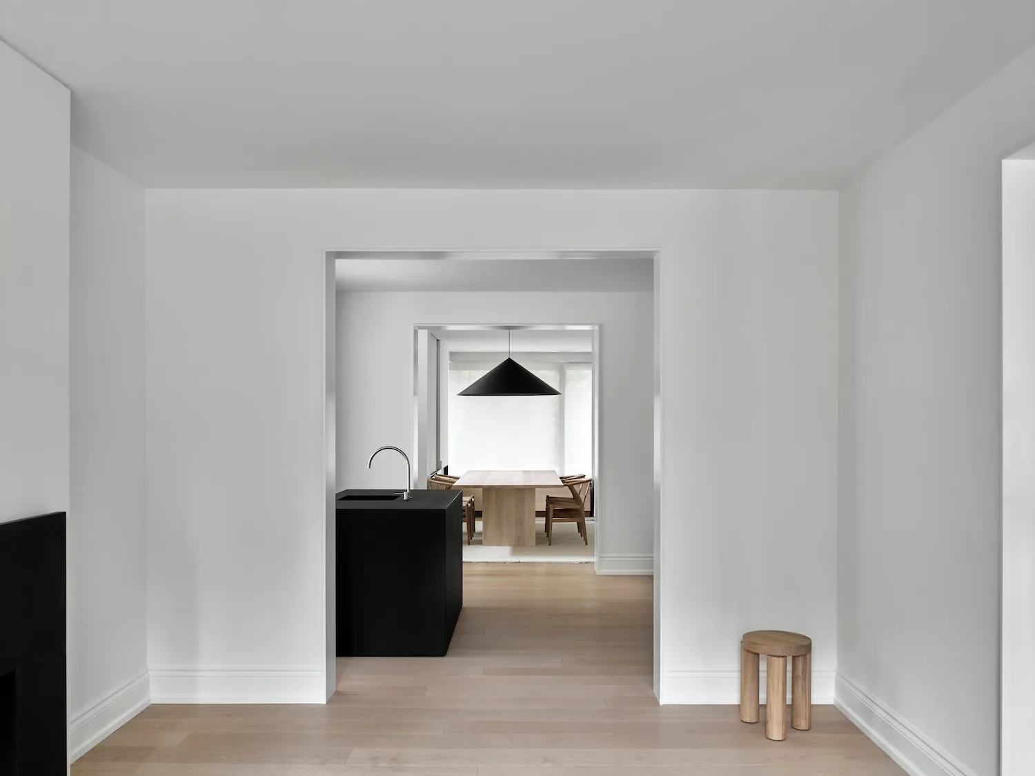 A modern minimalist kitchen with a wooden countertop and pendant light fixture.