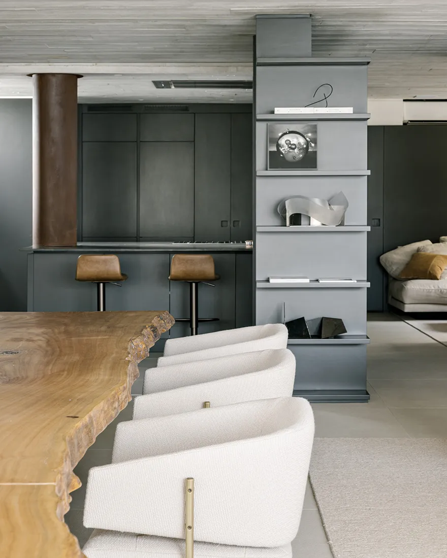 Modern living room featuring a wooden table, concrete shelves, and fabric upholstered chairs and sofa.