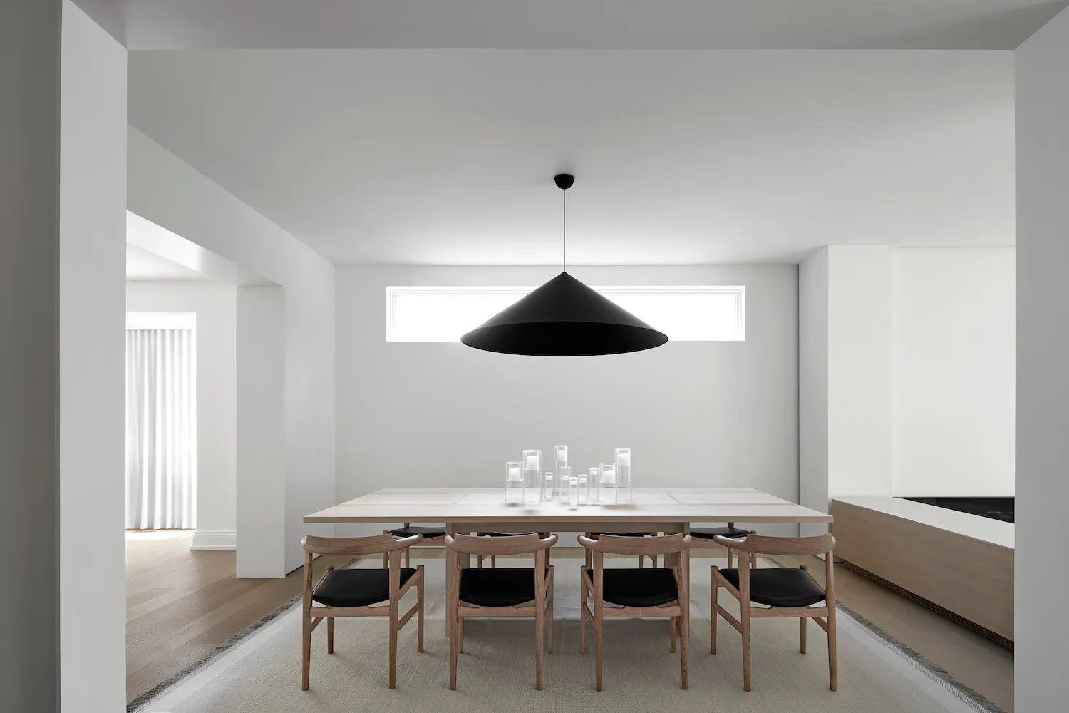 A modern minimalist dining room with a wooden dining table and chairs.