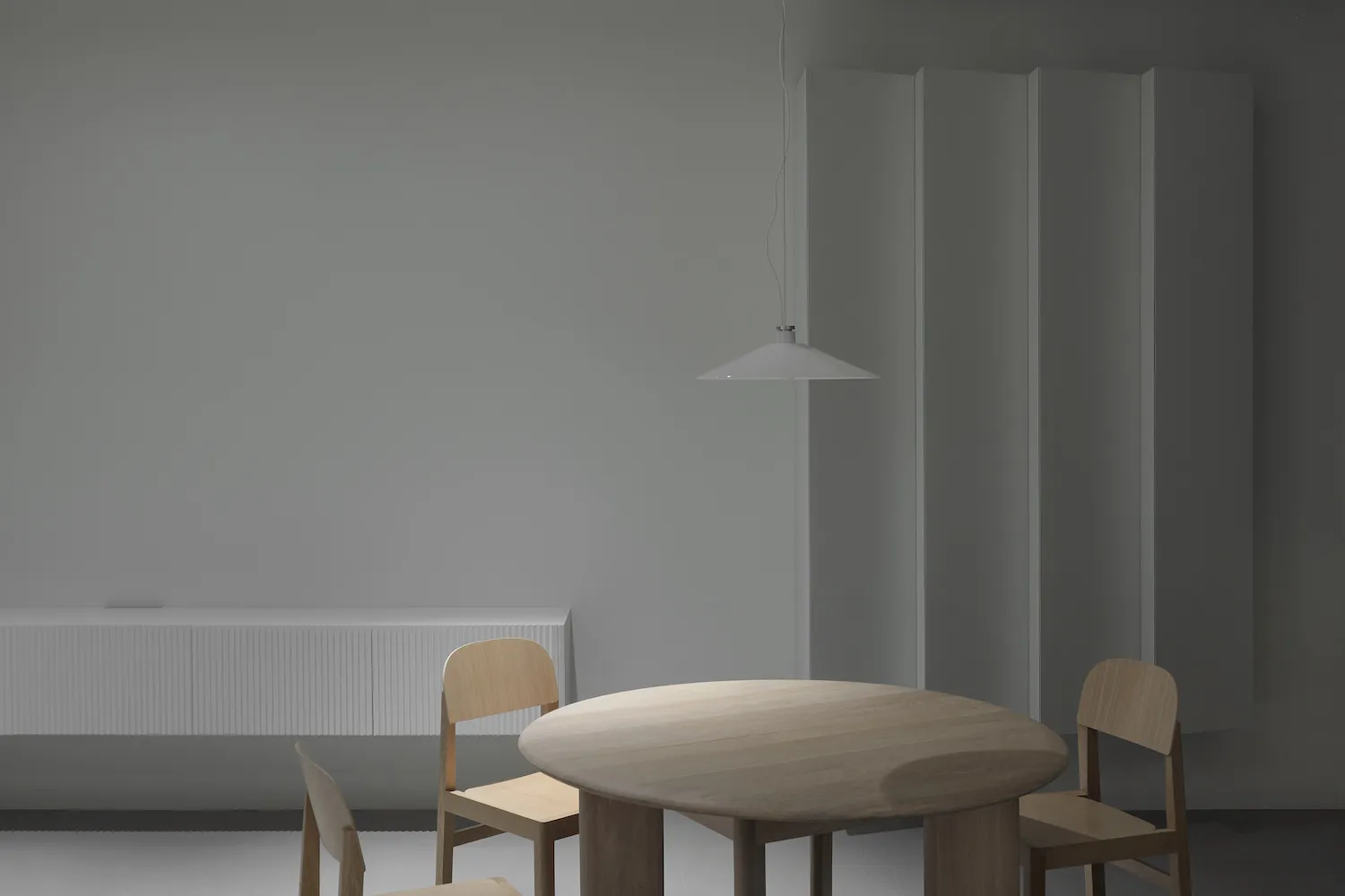A modern minimalist dining room featuring a wooden dining table and chairs.