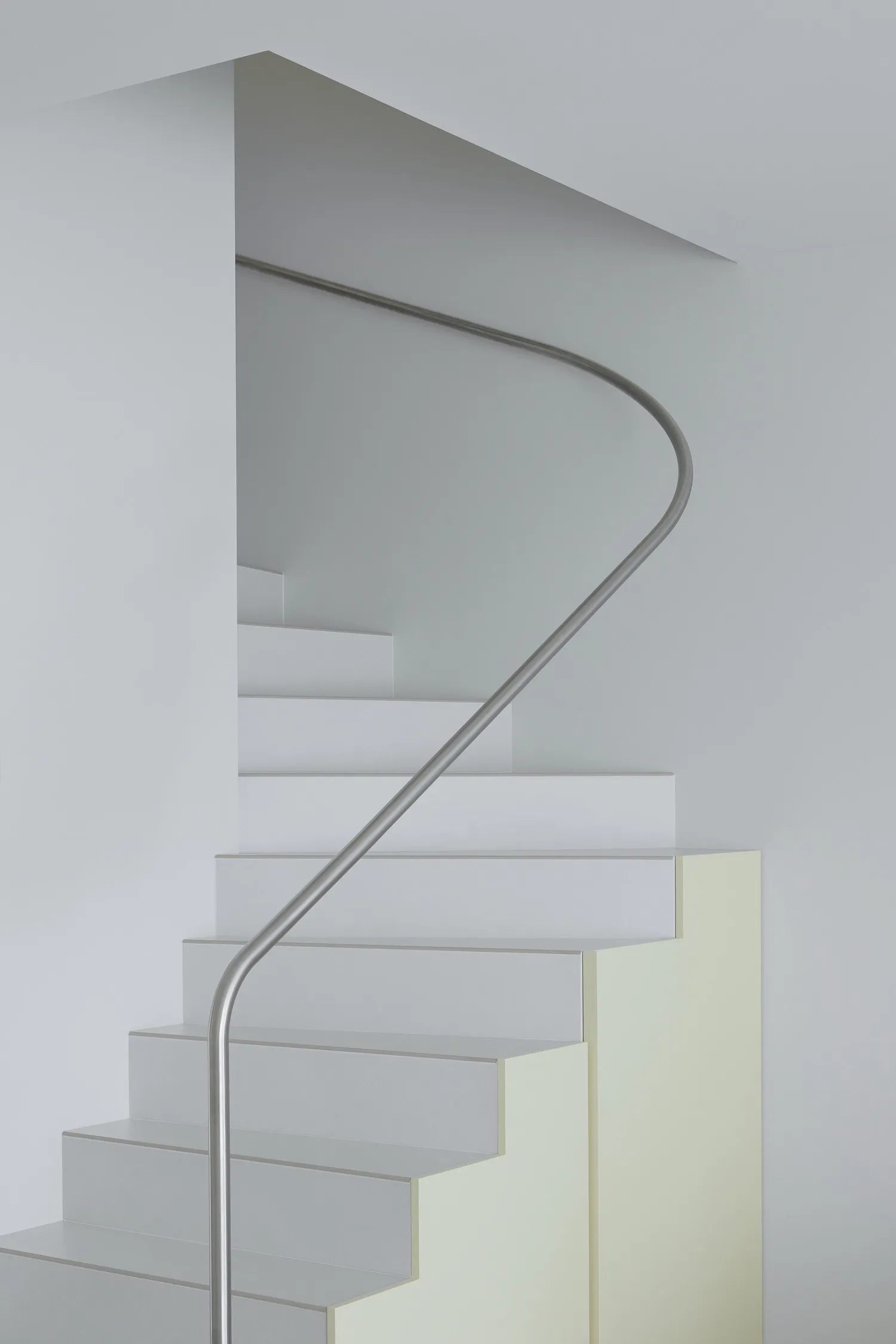 A modern white staircase with a steel handrail