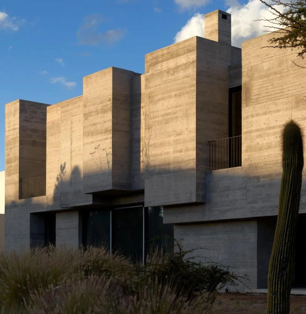 A modern exterior building made of concrete with a geometric design and large windows.